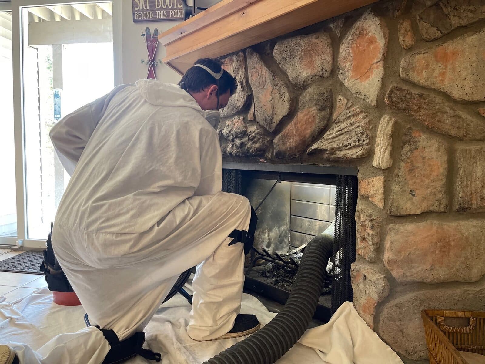 Technician in white protective suit sweeping a stone fireplace